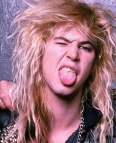 a man with long blonde hair and piercings on his face is making a funny face