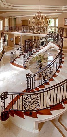 an elegant staircase with chandelier and marble flooring in a large home's entryway