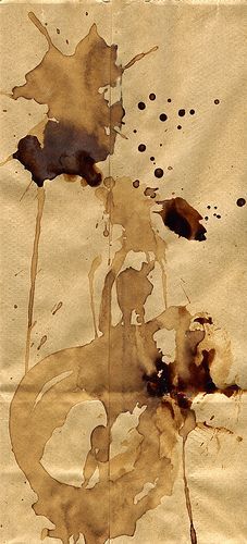 a piece of brown paper with ink splatters on it and some black spots