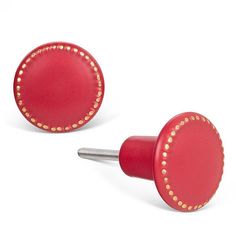 pair of red leather studded cufflinks with gold dots on each end and an oval hole in the middle