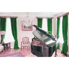 a grand piano in a living room with green curtains