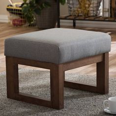 a small foot stool sitting on top of a carpeted floor next to a coffee cup