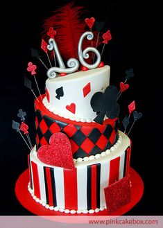 a red and white cake decorated with hearts, playing cards and a number on top