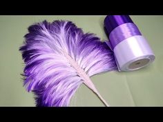 a purple and white feather sitting next to a roll of tape