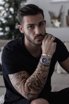 a man with tattoos sitting on a couch