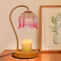 a pink glass lamp sitting on top of a wooden table next to a framed photo