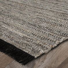 an area rug with fringes on top of it and wood flooring in the background