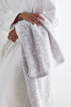 a woman wrapped in a white towel with an intricate design on the front and back