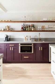 a kitchen with purple cabinets and white counter tops, gold trimmings on the shelves