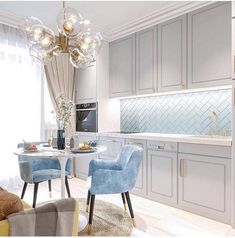 a dining room and kitchen area with blue chairs, white counter tops and light colored cabinets