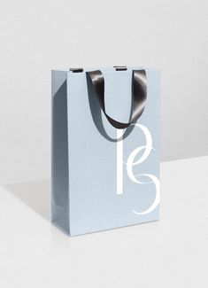 a blue shopping bag sitting on top of a white table next to a black ribbon