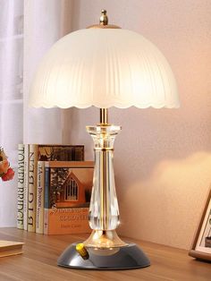 a table lamp on top of a wooden desk next to a book shelf and window