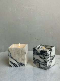 two marble candle holders sitting on top of a white countertop next to each other