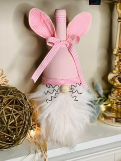 a pink vase with bunny ears on top of a shelf next to other ornaments and decorations