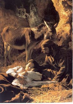 an image of a man and baby laying in the grass with donkeys behind him