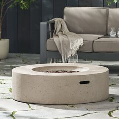 a concrete fire pit sitting on top of a patio next to a couch and table