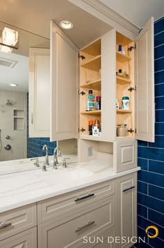 a bathroom with white cabinets and blue tile on the walls, along with an open medicine cabinet