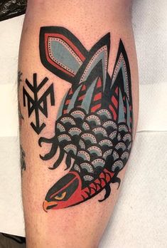 a tattoo on the leg of a man with fish and arrow design in black and red