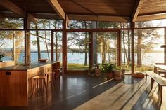 an open kitchen and dining area with large windows overlooking the water in front of it