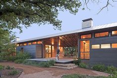 a modern house with large windows on the front and side of it, surrounded by trees