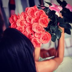 a woman holding a bouquet of roses up to her face