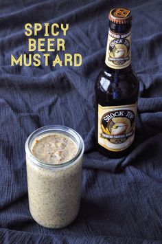 a bottle of beer sitting next to a glass jar filled with liquid on top of a blue cloth