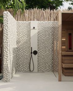 an outdoor shower with white pebbles and black faucet