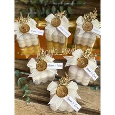 four small clear vases filled with white flowers and gold accents, each containing a monogrammed ribbon