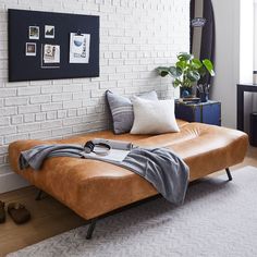 a bed sitting on top of a wooden floor next to a white brick wall