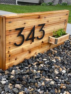 a wooden mailbox sitting on top of a pile of rocks next to a sidewalk