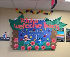 a welcome back sign hanging from the side of a wall in an office building with flowers on it