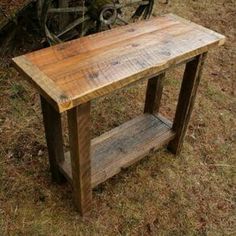 a wooden table sitting on top of a grass covered field next to an old bike