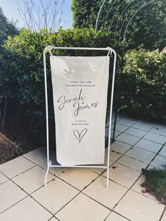 a white sign sitting on top of a sidewalk