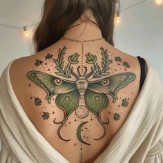 the back of a woman's neck with a green moth tattoo on her left shoulder