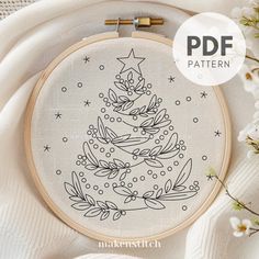 a cross stitch christmas tree with stars and snowflakes on it is surrounded by white flowers