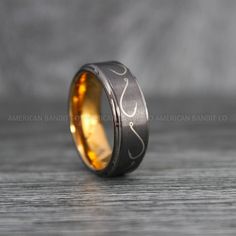 the wedding band is made from black and gold inlays with an intricate design