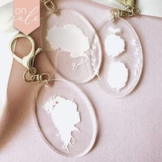 two clear acrylic keychains with white silhouettes on them and a pink background