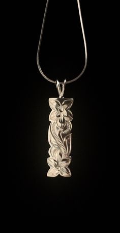 a silver necklace with an intricate design on the front and back of it, hanging from a