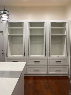 an empty kitchen with white cabinets and wood floors