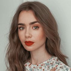 a woman with long brown hair and red lipstick on her lips is looking at the camera