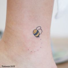 a small tattoo on the ankle of a woman's foot with a yellow and black bee