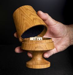 a hand holding a wooden object with dices in it's center and inside