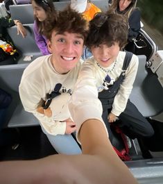 two young men are taking a selfie in the back of a vehicle with their arms around each other