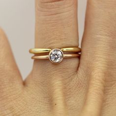 a woman's hand with a gold ring and a white diamond on the band