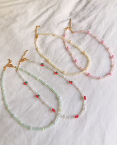 three necklaces with pearls and beads on a white sheet