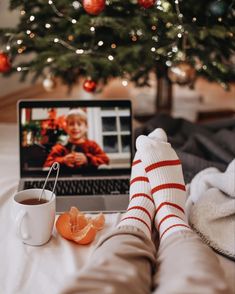 a person laying in bed with their feet propped up next to a coffee cup and laptop