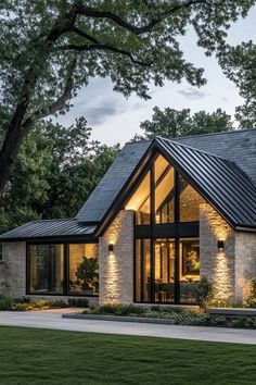 a modern house is lit up at night with lights on the windows and stone walls