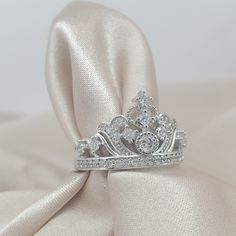 a tiara ring sitting on top of a satin fabric