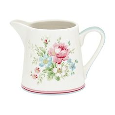 a white pitcher with pink and blue flowers painted on the side, sitting in front of a white background