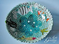 a bowl with fish and bubbles painted on it's sides, sitting on a blue surface